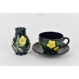 A Moorcroft pottery 'Buttercup' pattern cup and saucer designed by Sally Tuffin, together with a