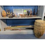 A collection of African carved wooden busts, musical instruments, spears, some with beaded