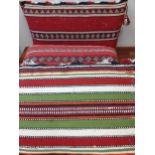 Three mid 20th Century Eastern rug cushions in various designs and colours, approx 66cm x 40cm.