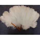 An early 20th Century white ostrich feather fan having 19 amber coloured wands with an Art Deco