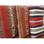 Three mid 20th Century Eastern rug cushions in various designs and colours, approx 66cm x 40cm.