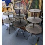 A set of three wrought metal shop cake stands having three graduated tiers and scrolled legs, 131h x