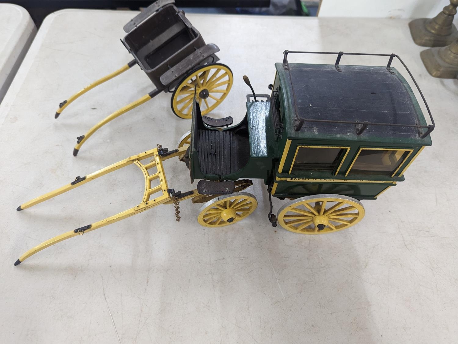 A model horse drawn carriage constructed of wood and metal parts, painted green and yellow with Kent