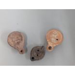 A group of three possibly Roman/Classical terracotta oil lamps, to include one having circular