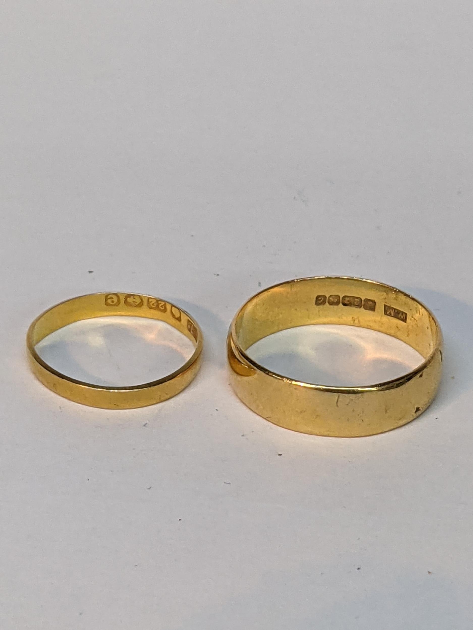 A 22ct yellow gold wide band ring, and a smaller 22ct yellow gold band Location: