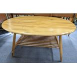 A vintage Ercol blonde elm and beech oval topped coffee table with magazine rack below, 44cm h x