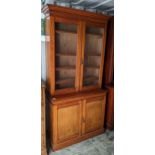 A Victorian walnut bookcase having twin glazed doors above two cupboard doors and on a plinth