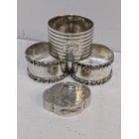 Three early 20th century silver napkin rings together with a silver engraved pill box, 126.5g