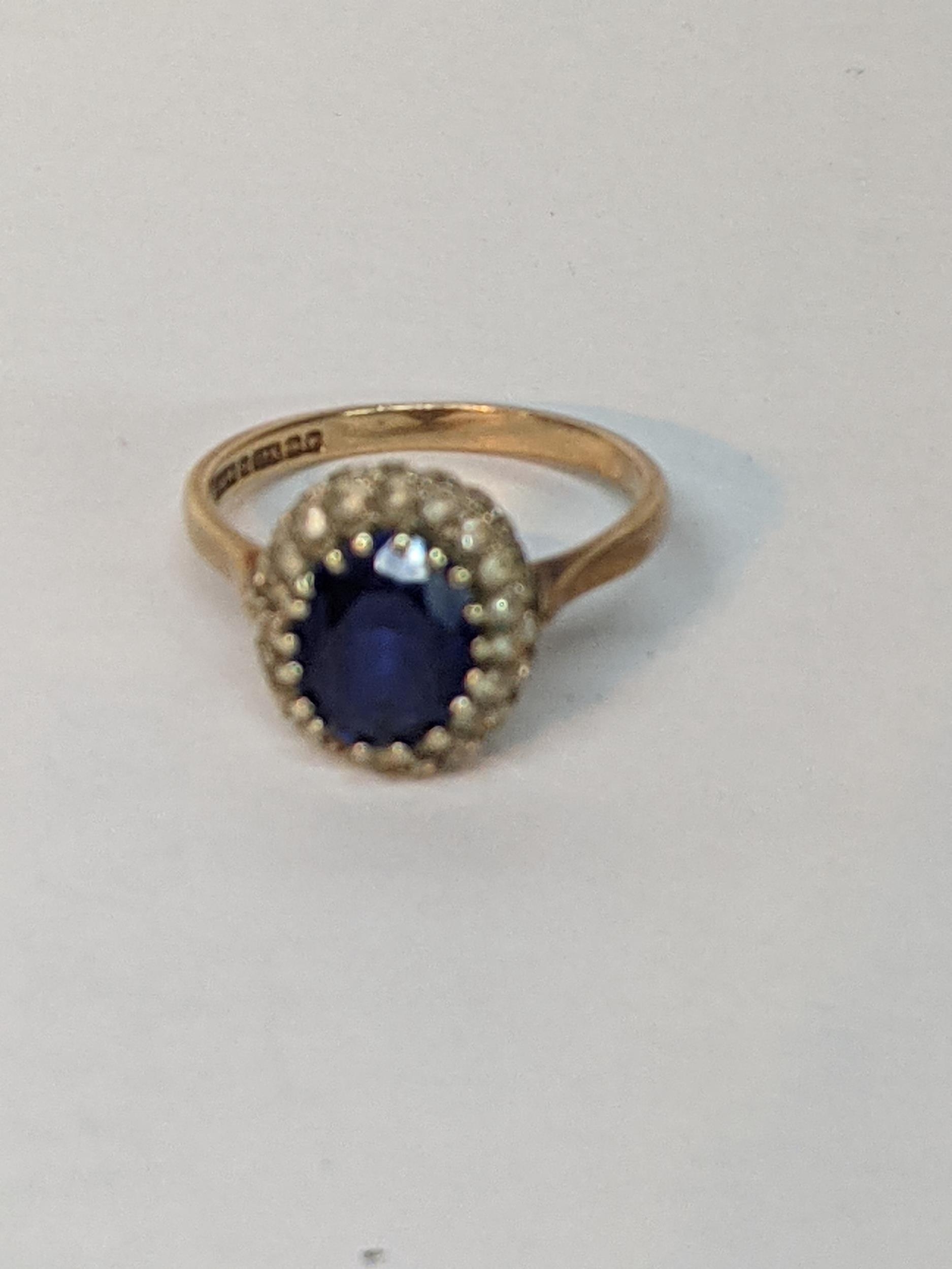 A 9ct rose gold ring set with an oval blue stone (possibly a heavily treated sapphire) surrounded by