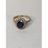 A 9ct rose gold ring set with an oval blue stone (possibly a heavily treated sapphire) surrounded by