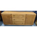 A vintage Ercol blonde elm Windsor sideboard having three drawers flanked by two cupboard doors,