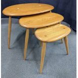 A nest of three vintage Ercol blonde elm and beech pebble tables on turned splayed legs, largest