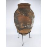 A 19th/20th century terracotta olive pot, with raised banded ornament on a wrought metal base, for