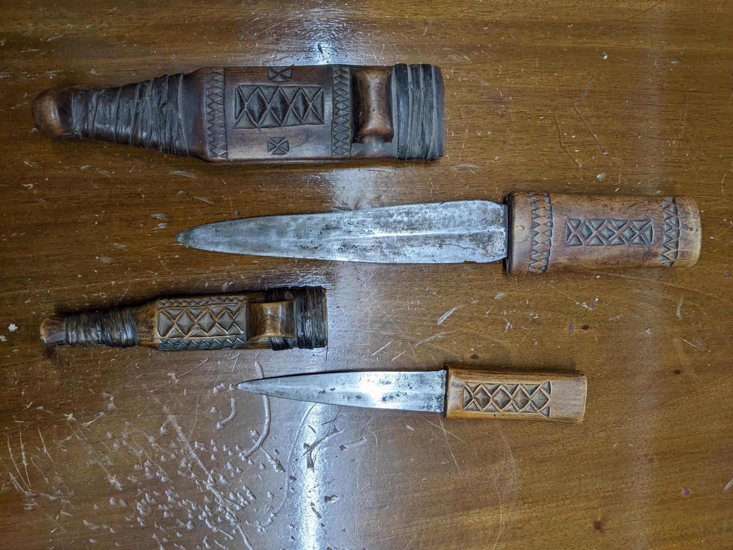 Two early to mid East African wooden handled daggers in wooden sheaths with carved decoration