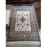 A hand woven Tunisian rug, floral design on a white ground multi-guard border, tasselled ends, 184cm