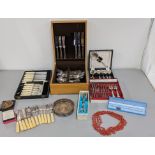 A mixed lot of silver plated cutlery, boxed flatware, salad tongs and others together with a red