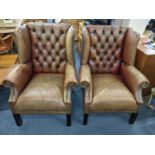 A pair of mid 20th century tan leather wingback armchairs having button and stud back upholstery and