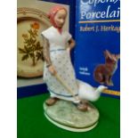 Royal Copenhagen - a young lady wearing a salmon pink headscarf holding a stick with a goose by