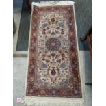 A small handwoven Isfahan style rug with floral design on a white ground, triple guard border,