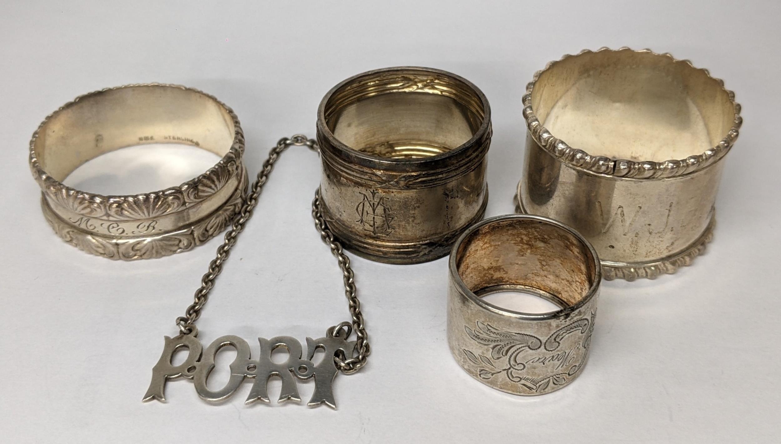Two sterling silver napkin rings together with two white metal smaller napkin rings, and a port