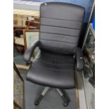 A modern black leather swivel office armchair. Location: