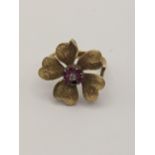 A yellow metal ring in the form of a flower inset with a diamond and purple rubies A/F, total weight