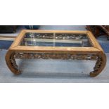 A mid 20th century Chinese coffee table having a glass top and carved scrolled legs, 32cm h x 92.5cm