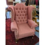 A mid 20th century wingback armchair having button and stud back upholstery and on short cabriole