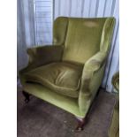 An early/mid 0th century wingback green upholstered armchair on short mahogany cabriole legs