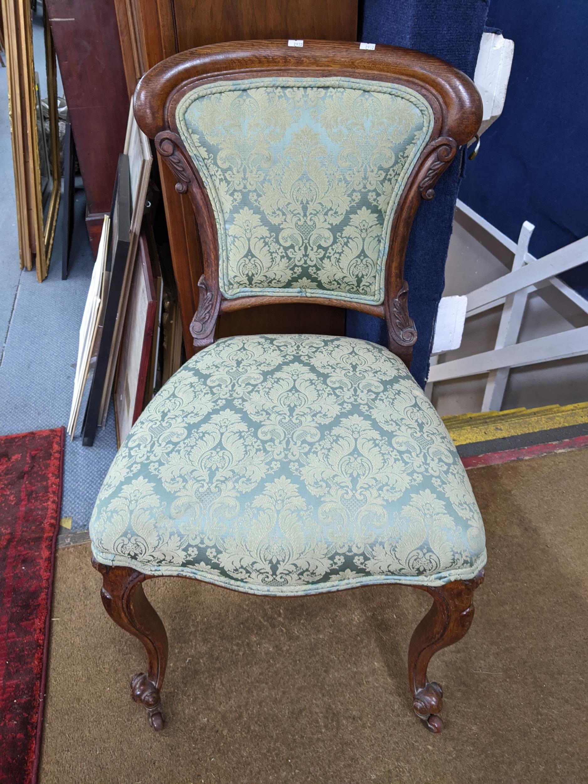 A late 19th/early 20th century French oak side chair having carved c scrolls and on front cabriole