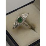 A white metal Art Deco inspired Lozenge shaped ring having a central emerald surrounded by diamonds,