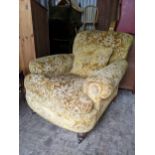 A circa 1900 Howard style low and deep armchair on turned front legs, and on later castors, 83cm h x