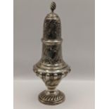 A late Victorian silver sugar caster having embossed reeded body, 'C' scrolls and initials,