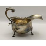 An early 20th century silver sauceboat having a scroll shaped handle and on three horse hoof