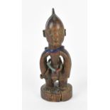 A Nigerian Yoruba male twin figure ibedji, with elaborate crested coiffure, with stringed bead