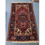A Turkish hand woven blue and red ground rug having tasselled ends and geometric designs, 210cm x