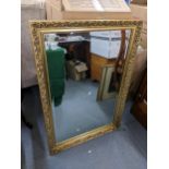 A reproduction gilded wall mirror having a moulded frame and bevelled glass, 103cm h x 72.5cm w