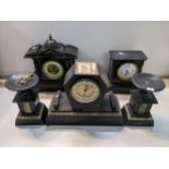 Three black slate cased mantel clocks the Art Deco example with a pair of side pieces Location: