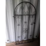 A wrought metal, black painted garden gate having an arched top and scrollwork frame, 167.5h x