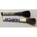 Two Chinese calligraphy brushes, one having a bone and bulbous porcelain handle, decorated with