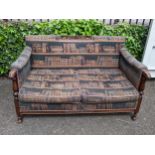 A mid 20th century two seater sofa having a carved top rail, scrolled arms supported by reeded