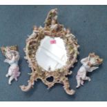 An early to mid 20th century porcelain wall mirror adorned with cherubs, flora and a young lady