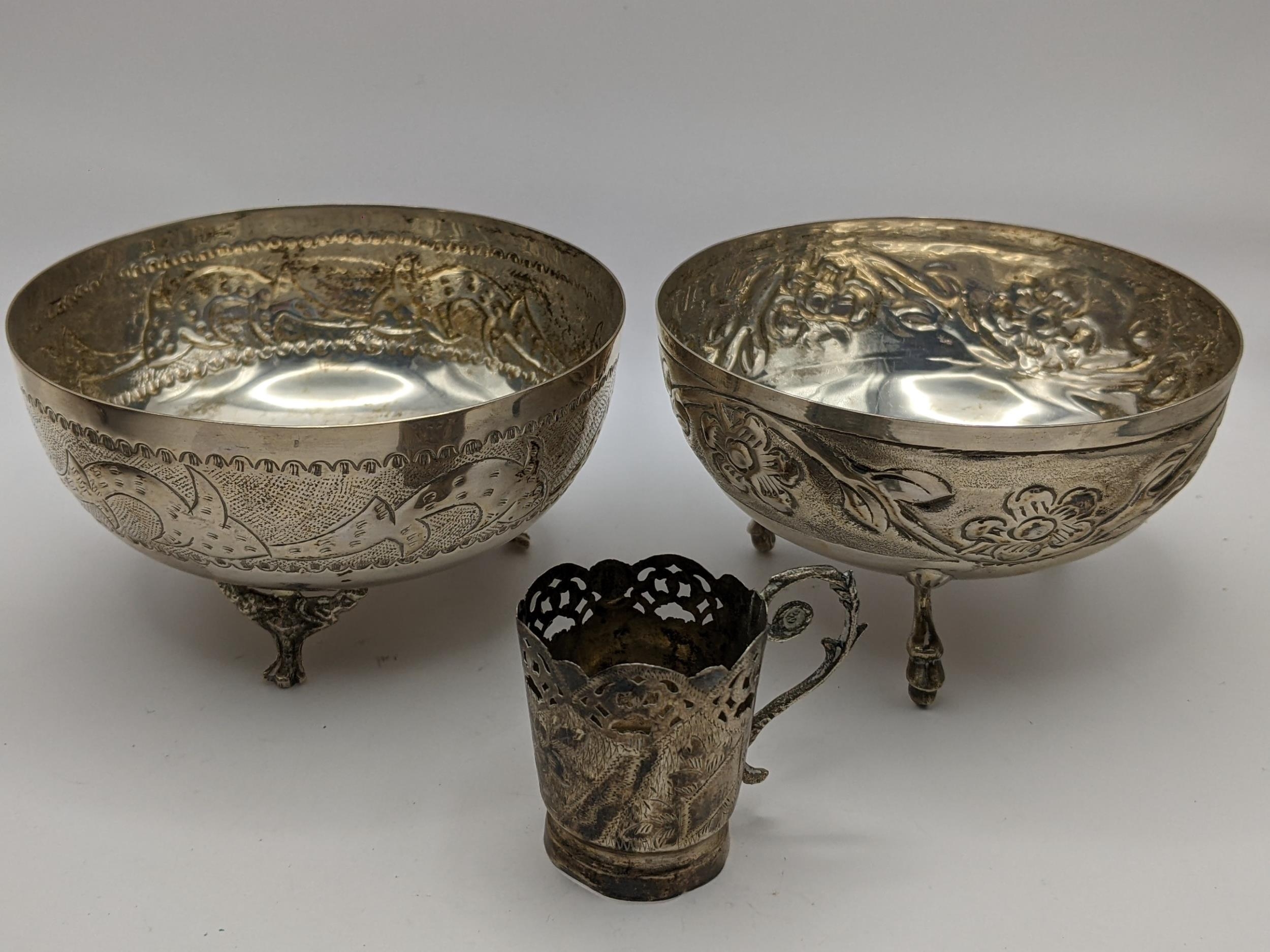 A pair of white metal bowls having embossed decoration, together with a white metal cup holder,