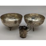 A pair of white metal bowls having embossed decoration, together with a white metal cup holder,