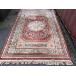 A Chinese red ground rug having a central motif and multi-guard borders, 280cm x 182cm Location: