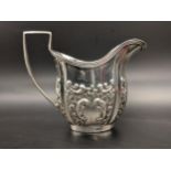 An early 20th century silver cream jug with embossed floral decoration, hallmarked Chester 1906,