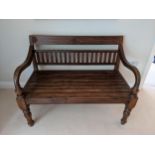 An Indonesian hardwood bench with a carved rail on splat back, the slatted seat on turned legs,
