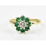 An 18ct yellow gold, emerald and diamond floral cluster ring, with central brilliant cut diamond