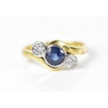 An 18ct yellow gold, diamond and blue sapphire ring, with central bezel set sapphire flanked with