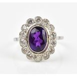 An 18ct white gold, amethyst and diamond cluster ring, with central oval amethyst with a halo of